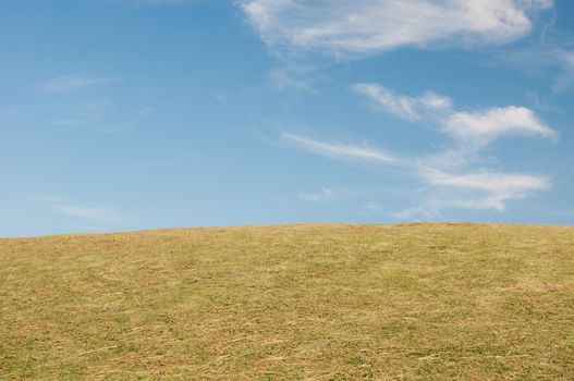 Green sloping  meadows and clouds with blue sky