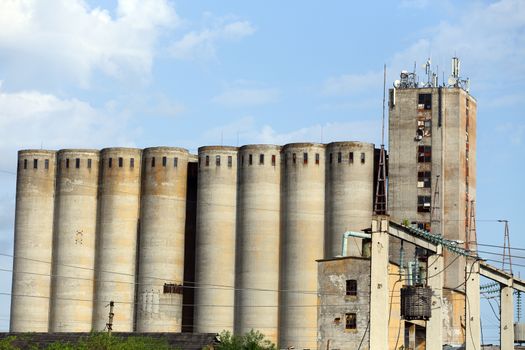  old concrete grain elevator complex against a blue sky. 