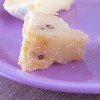 Pecorino cheese with pepper, close up over purple plate