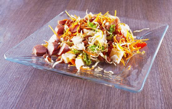 Salad with sausage, cheese, carrots, beans over glass plate