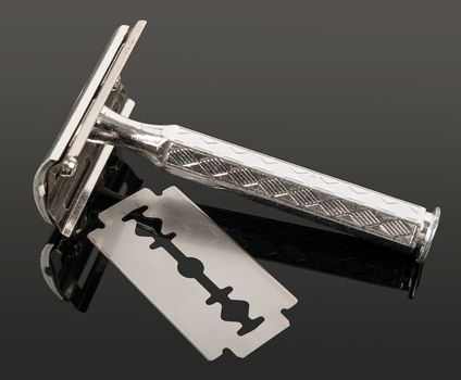 vintage razor and blade with reflection isolated on gray background