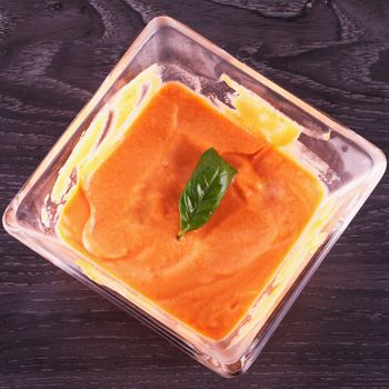 Gazpacho in a glass square cup over wooden table