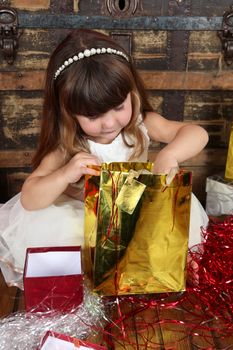 Little girl in a dress opening christmas gifts