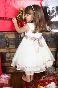 Little girl in a dress opening christmas gifts