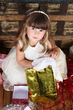 Little girl in a dress opening christmas gifts