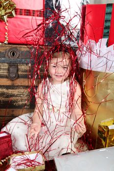 Little girl in a dress opening christmas gifts