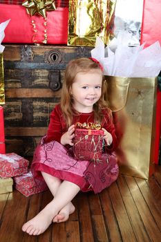Little girl wearing a christmas dress looking at gifts