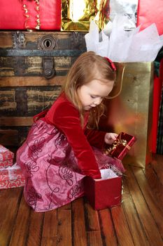 Little girl wearing a christmas dress looking at gifts