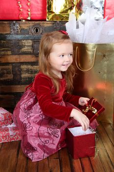 Little girl wearing a christmas dress looking at gifts