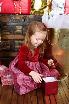 Little girl wearing a christmas dress looking at gifts