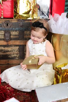 Little girl wearing a christmas dress looking at gifts