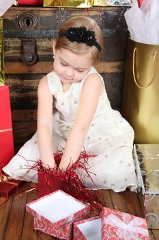 Little girl wearing a christmas dress looking at gifts