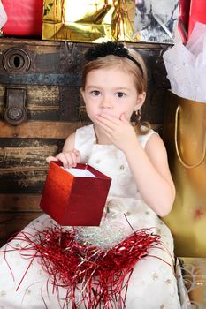 Little girl wearing a christmas dress looking at gifts
