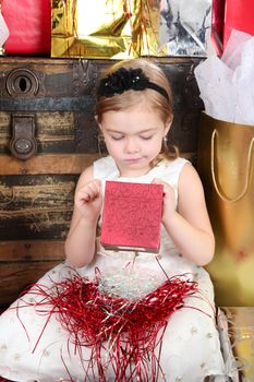 Little girl wearing a christmas dress looking at gifts