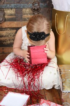 Little girl wearing a christmas dress looking at gifts