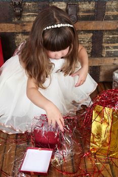 Little girl wearing a christmas dress looking at gifts