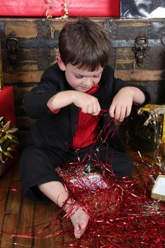 Little boy wearing a christmas suit looking at gifts