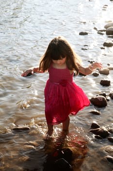 Little girl playing in a shallow stream of water