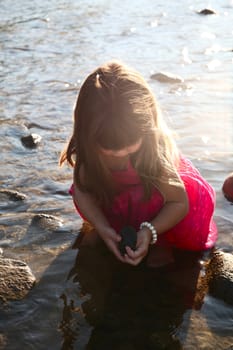 Little girl playing in a shallow stream of water