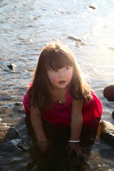 Little girl playing in a shallow stream of water