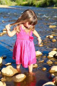 Little girl playing in a shallow stream of water