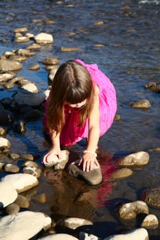 Little girl playing in a shallow stream of water