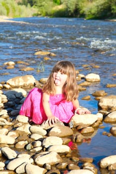 Little girl playing in a shallow stream of water