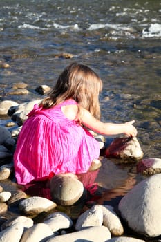 Little girl playing in a shallow stream of water