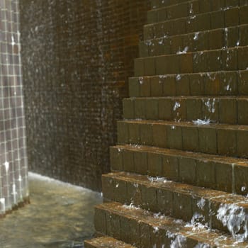 Water falling down on brown bricks