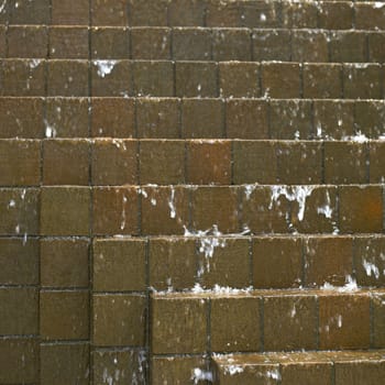 Water falling down on brown bricks