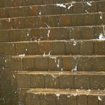 Water falling down on brown bricks