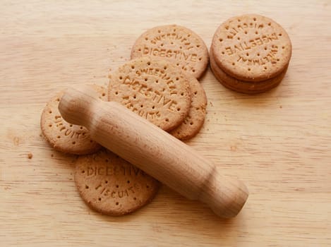 Starting to crush digestive biscuits with a rolling pin on a wooden board