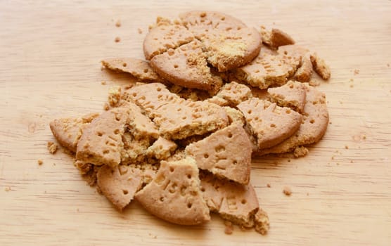 Pile of crushed digestive biscuits and crumbs on a wooden board