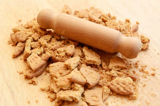Crushing digestive biscuits into small pieces and crumbs with a wooden rolling pin