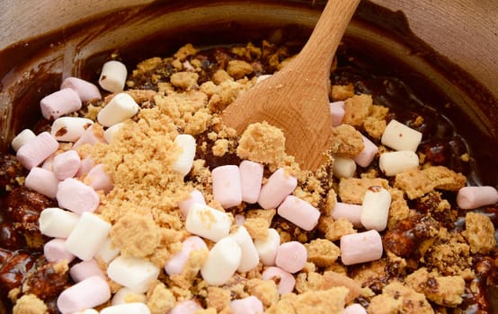 Combining melted chocolate with mini marshmallows and crushed biscuits in a rocky road recipe