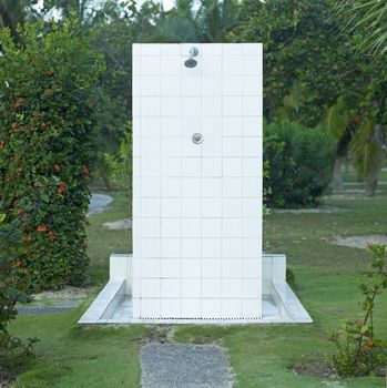 White outdoor shower in the middle of tropical trees and bushes