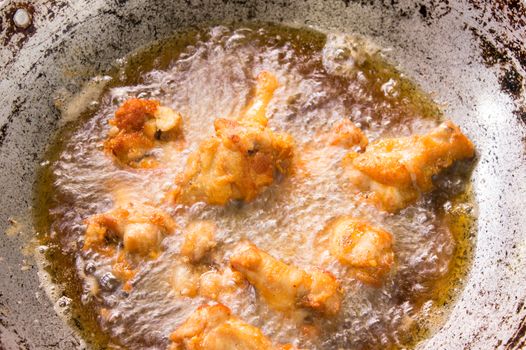 Frying chicken drumstick in boiling oil iron pan