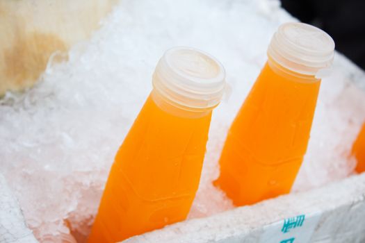 orange juice bottles on ice at market