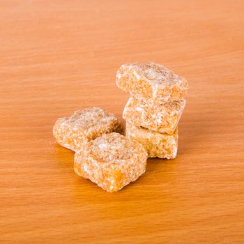 Brown cane sugar cubes on a wooden background