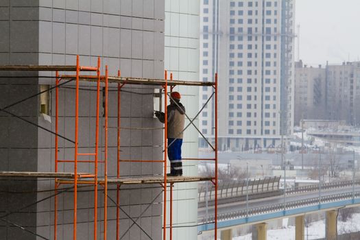 A construction worker on a high wall - Stock Image