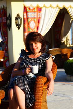 Woman sitting in a chair, drinking coffee - Stock photos