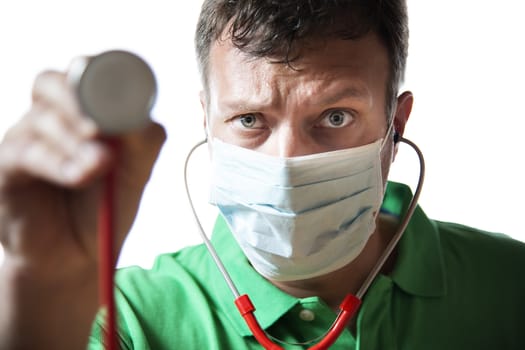 Desperate doctor with surgical mask in green shirt holding his stethoscope