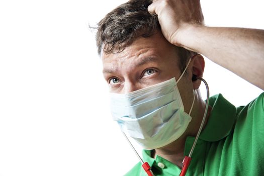 Helpless, anxious and perspiring doctor in a green shirt with a red stethoscope and surgical mask