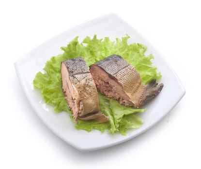 Pieces of smoked hunchback salmon with fresh green lettuce on the white plate