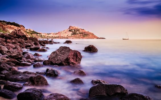 Ocean coastline with village in the background at sunrise, Castelsardo, Sardinia, Italy