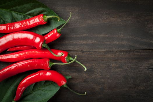 Chili peppers with leaves on wooden table background with copy space. Top view