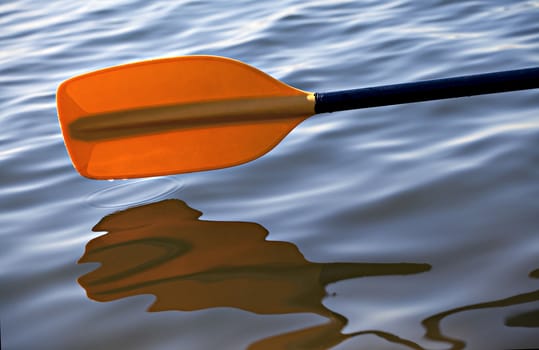Kayak paddle on side of a boat at still river water