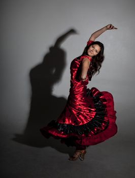 Young woman dancing flamenco, studio shot, gray background