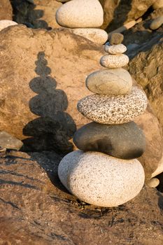 The sun sets bathing polished stacked rock on the sea shore