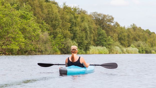 Woman on a small river in rural landscape, the Netherlands